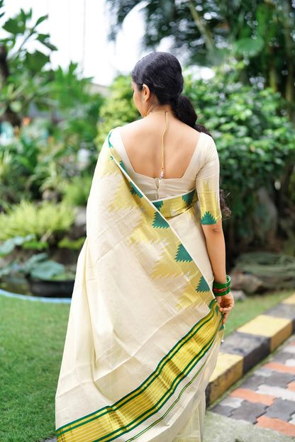 Woman in a Golden Tissue Saree with Green Temple Motifs standing in a garden.