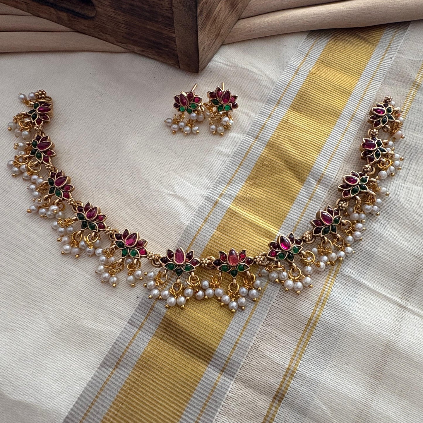 Necklace and earrings set on a saree fabric with a wooden box in the background