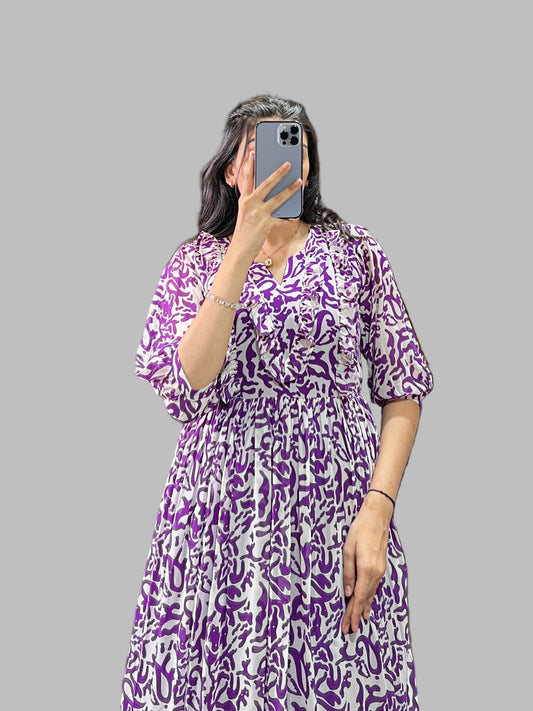 Person wearing a purple patterned dress taking a mirror selfie.